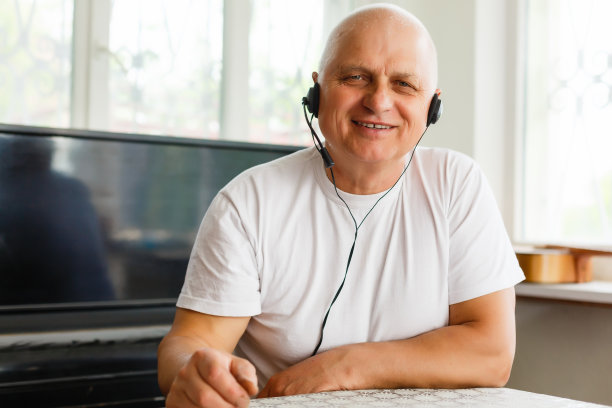 镜头拉近了快乐的爷爷看着镜头，和成年的孩子们聊天，或者坐在家里的沙发上和朋友视频通话。能参与谈话的讨人喜欢的老人。图片下载