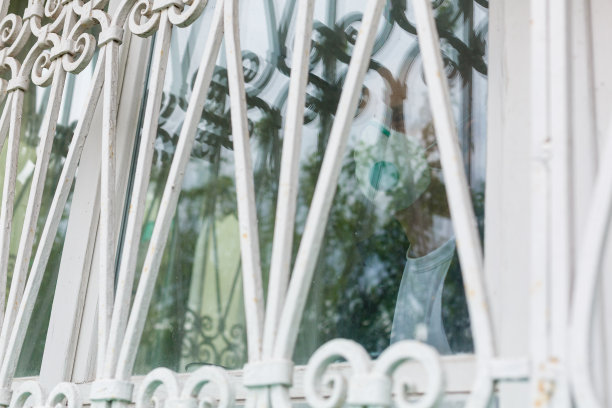 冠状病毒隔离。老人戴着防护口罩躲在窗户后面，避免被COVID-19传染——责任和预防理念图片下载