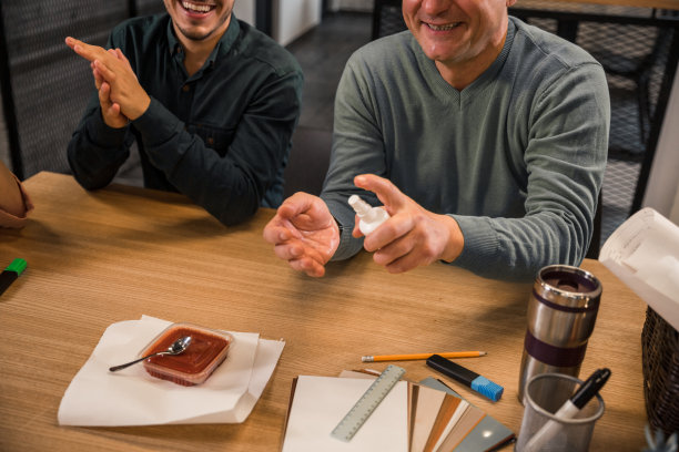 一名男子在办公室午餐前用杀菌喷雾剂喷洒双手图片下载