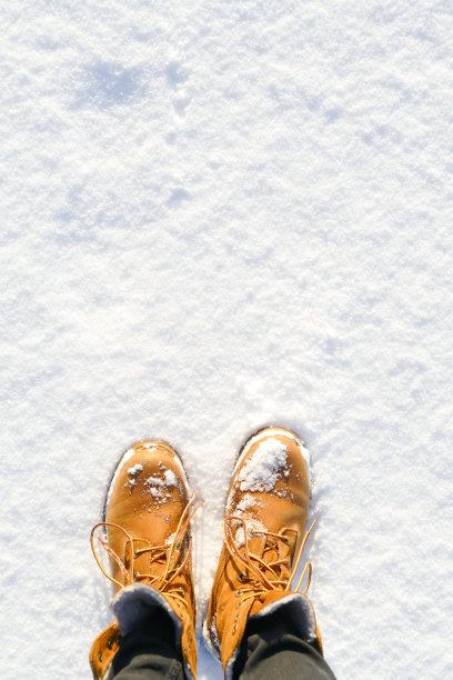 俯视图黄色的鞋子/靴子在雪地里。图片下载