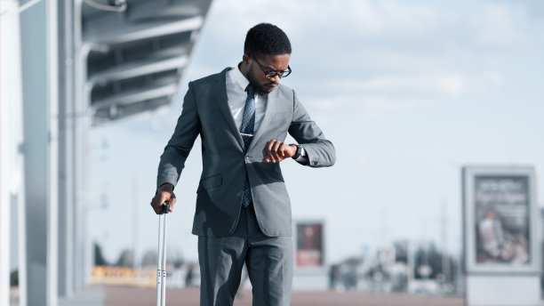 带旅行箱的男子在机场检查时间，全景图图片下载