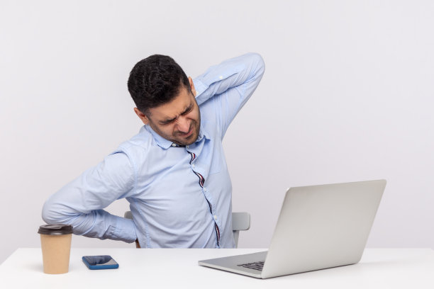疲惫的商人坐在办公室工作场所，用笔记本电脑，感到背部酸痛，按摩僵硬的肌肉图片下载
