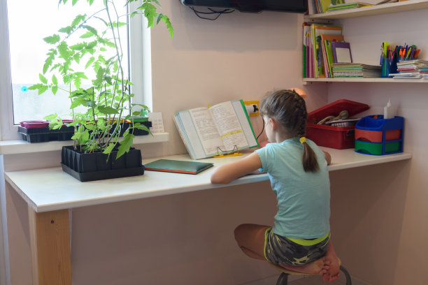 女孩正在家里的课桌上用课本教课图片下载