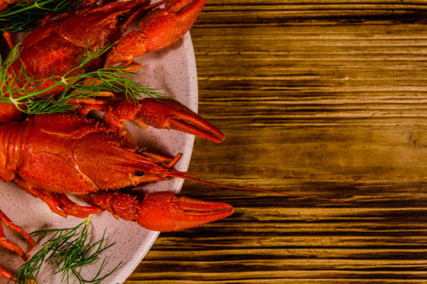 木桌上放着水煮小龙虾的盘子。俯视图图片下载