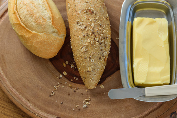 把面包、杂粮法棍和黄油卷在木板上(俯视图)。图片下载