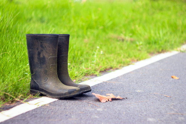 橡胶靴黑色与草的背景。图片下载