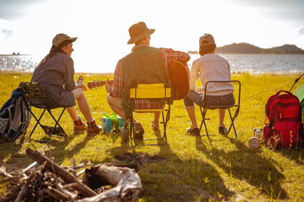 秋天的森林小径上，亚洲登山队在搭建好户外帐篷后，一起演奏着音乐，坐在一起喝着饮料。徒步旅行，徒步旅行，团队，森林，露营，活动概念。图片下载