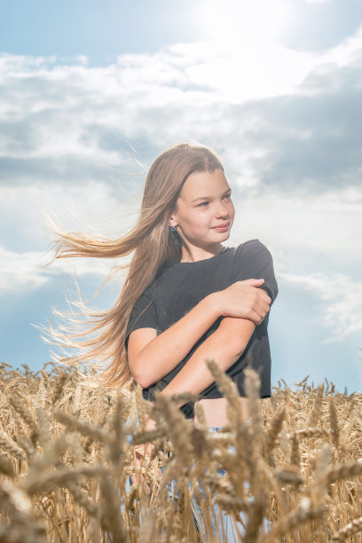 一个女孩举起双手在麦田里夏天。图片下载