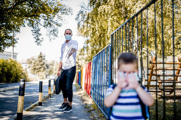 父子俩在上学前班。他们戴着医用口罩。图片下载