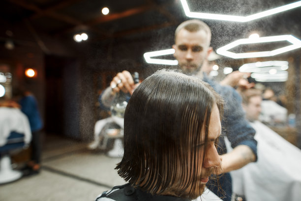 留着长发的年轻嬉皮士在现代的理发店里剪着时髦的新发型。专业理发师服务客户图片下载