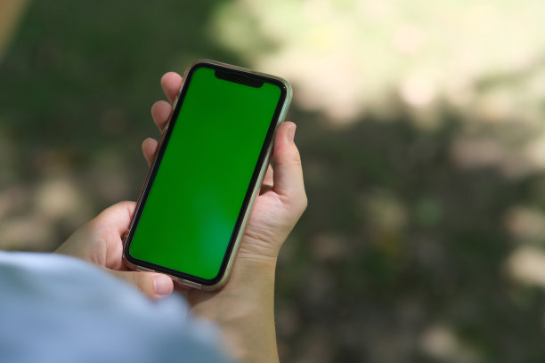 在阳光下，人们抱着绿色屏幕智能手机的肩膀视图图片下载