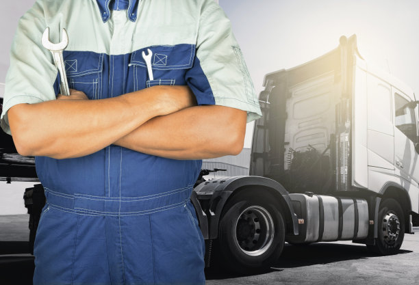 专业汽车修理工拿着扳手检查修理半挂车。卡车保养和维修。图片下载