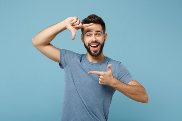 年轻开朗有趣的人在休闲衣服摆出孤立的蓝色墙壁背景，工作室肖像。人真诚情感生活理念。模拟拷贝空间。做相框手势。图片下载