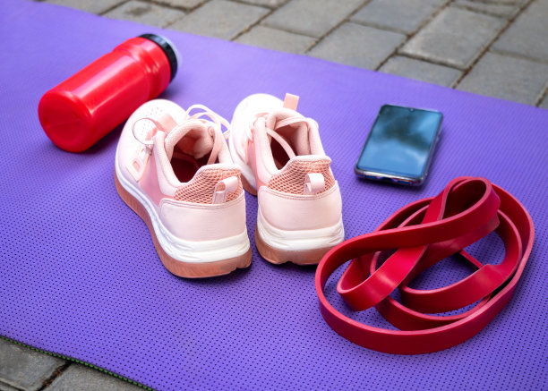 个人使用的健身配件和设备。女运动鞋，震动器，橡皮筋和手机作为一个定时器在垫户外铺地，选择性的焦点。图片下载