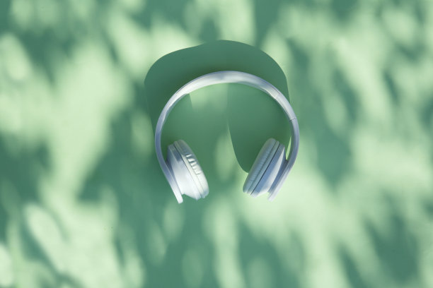 白色耳机在薄荷背景与树叶阴影。前视图。副本的空间。夏天平。图片下载