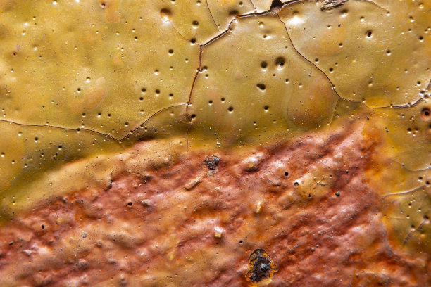 背景与旧的金属表面与锈迹和剥落的黄色油漆孔和裂缝。在高倍放大的精细细节。照片与软焦点和模糊的背景。图片下载