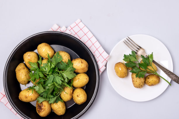 两盘有机年轻烤土豆装饰欧芹蓝色背景俯视图图片下载