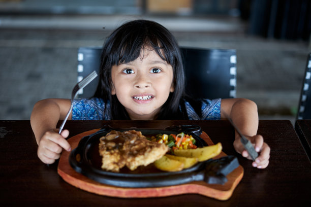 快乐的小女孩在当地餐厅吃牛排图片下载