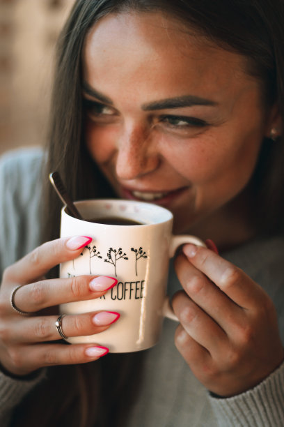 一个美丽的年轻女子在家里的窗户边喝咖啡的特写肖像图片下载