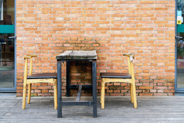 红色砖墙前的旧木制餐椅和餐桌图片下载