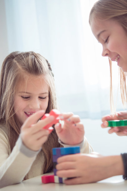两个年轻的女学生在课间玩彩色的魔方图片下载