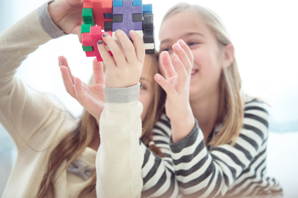 两个年轻的女学生在课间玩彩色的魔方图片下载