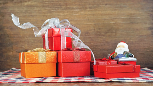 一组礼物盒与小圣诞老人的模型在条形布与木材背景。图片下载