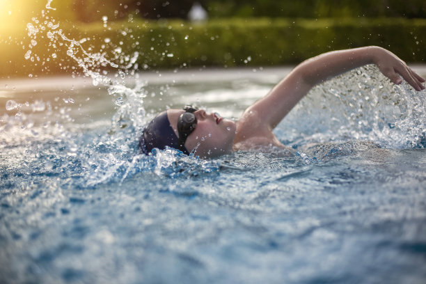 男孩在公共游泳池练习游泳图片下载