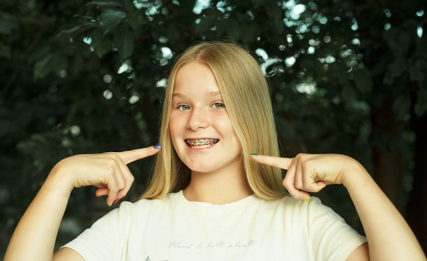 少女微笑指向牙套。图片下载