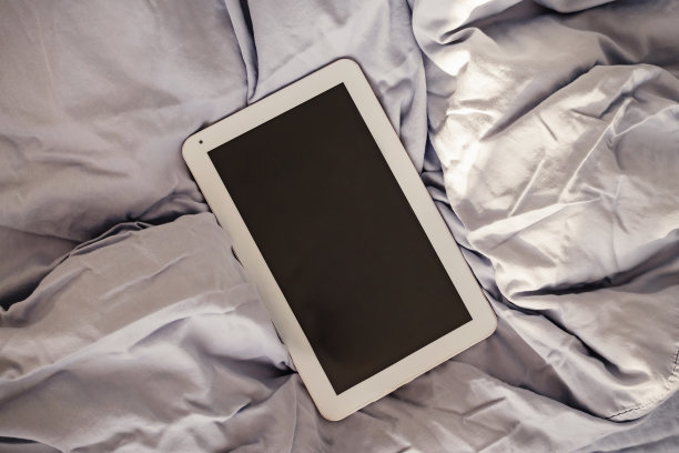 空屏幕平板上皱巴巴的床俯视图。图片下载