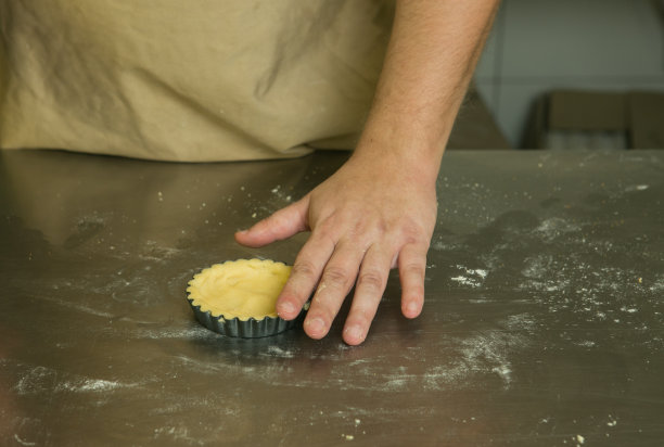 带水果的甜糕点的生产工艺。厨师用手做烘焙面团。厨师把揉好的面团放进模子里。图片下载
