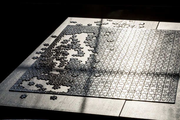 拼图游戏的碎片。桌子上有黑色的拼图。桌面游戏概念图片下载