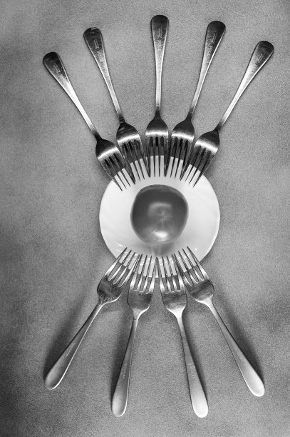 照片叉子周围的盘子像一个眼睛和睫毛特写在一个灰色的背景与番茄黑白图片下载