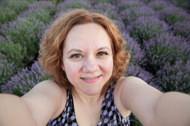 快乐的女人在薰衣草田看着相机微笑图片下载