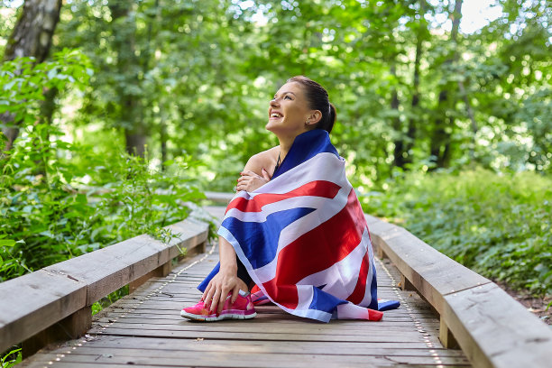 一个迷人的女孩在森林公园里与英国国旗摆姿势图片下载