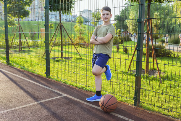 在一个阳光明媚的日子里，一个十几岁的男孩在篮球场上。图片下载