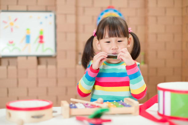 年轻的女孩在家里吹口琴接受家庭教育图片下载