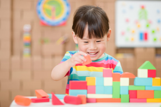 蹒跚学步的女孩玩创意玩具积木在家上学图片下载