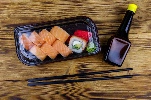 寿司卷费城在塑料盒在木桌上。前视图。装在塑料容器内的寿司供外卖或运送图片下载