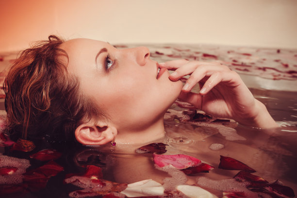 红头发的年轻女子用蜡烛做泡泡浴。图片下载