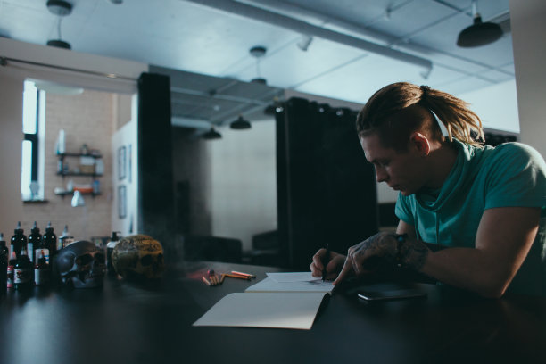 书法家的手。纹身艺术家在工作室俯视图的一张桌子旁画了一幅素描图片下载