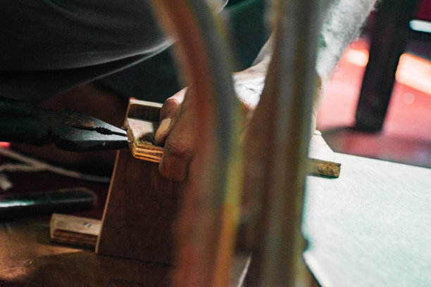 木匠正在用木头、钻床和其他工具工作。他正试图用木片做一些结构。图片下载