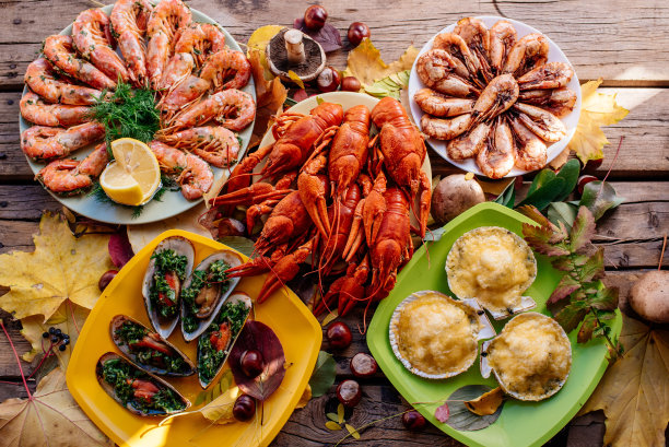 木桌上放着小虾、贻贝、小龙虾和扇贝图片下载