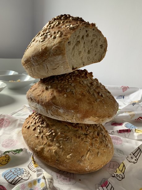 家里烤的三条面包。面包堆在一起。从上面的面包上切下一块。图片下载