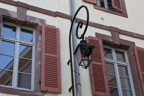 法国科尔马市中心一幢老住宅楼的外立面上，旧街灯的碎玻璃和新灯泡。这座建筑有坚固的红色木制百叶窗。图片下载