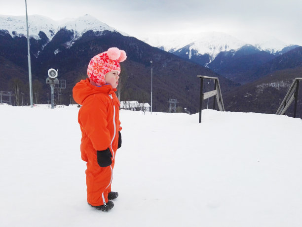 一个穿着滑雪服的孩子看着山坡图片下载