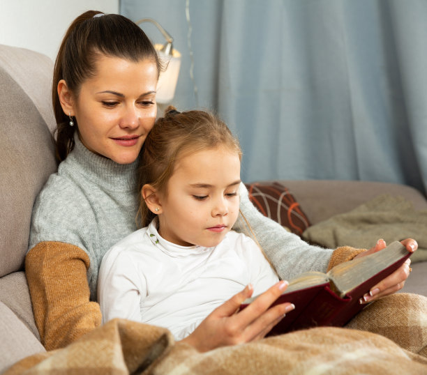 年轻的女人和女儿一起读一本有趣的书图片下载