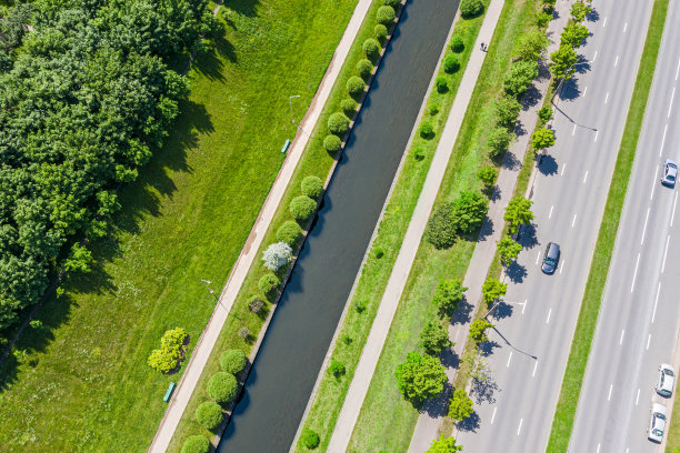 市区道路附近有绿树、草坪和水渠的郊区景观。晴天鸟瞰图图片下载
