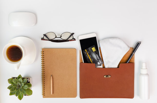 使用口罩、酒精凝胶、手机、咖啡杯、笔记本、眼镜和绿色树叶进行2019冠状病毒病防控的工作空间组合图片下载