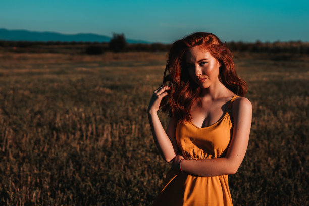 一个阳光明媚的夏日，年轻的红发姑娘在田野里的大自然中图片下载